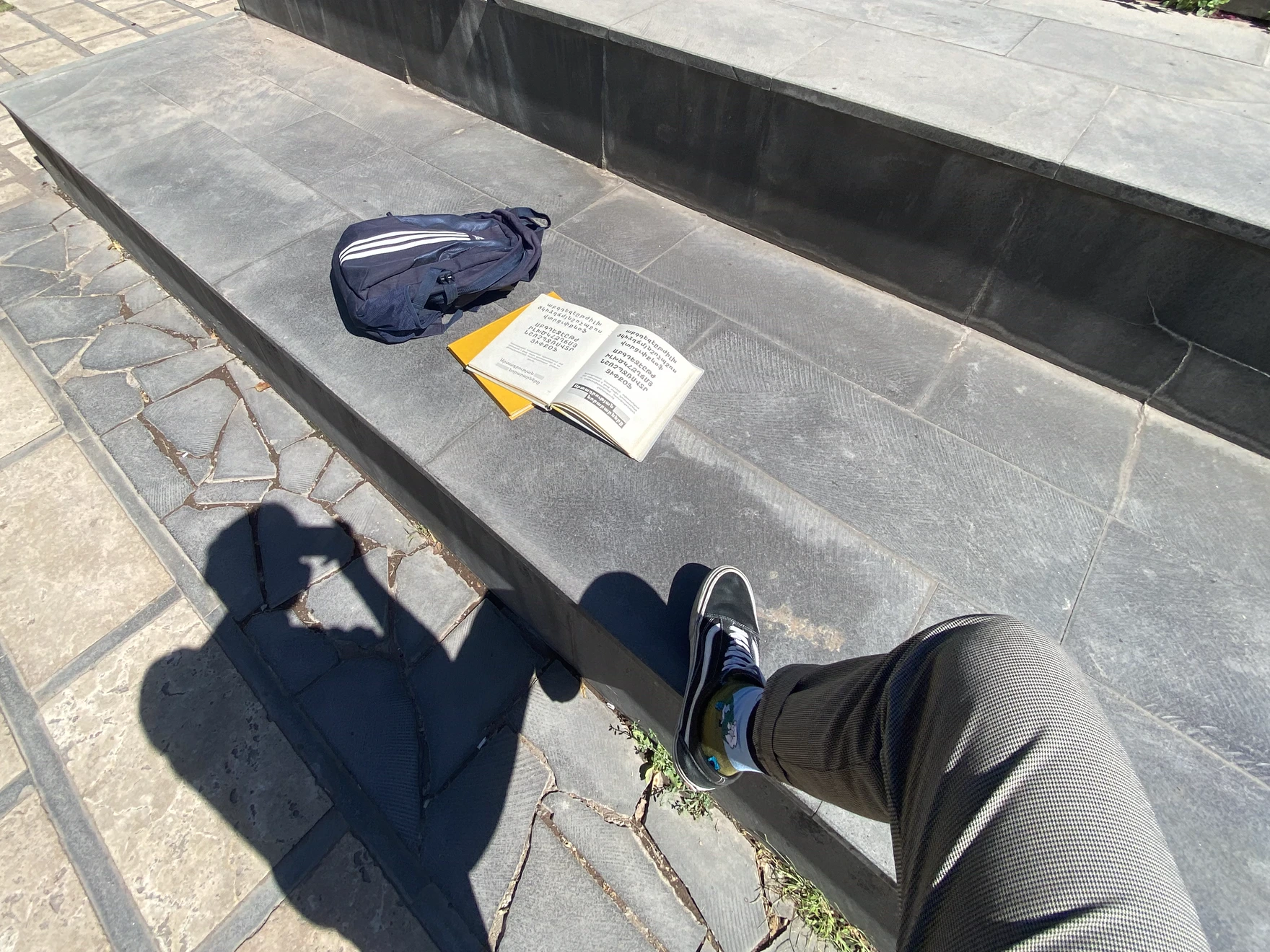 Type book and bag on park steps, photographer’s leg and shadow in frame